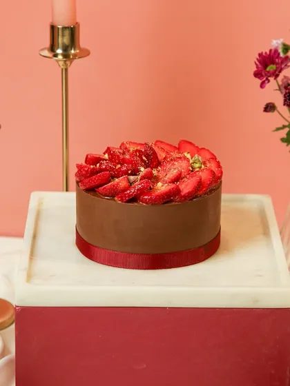 Our Chocolate Strawberry Gateau, a beloved classic, beautifully presented on a marble and wood cake stand.