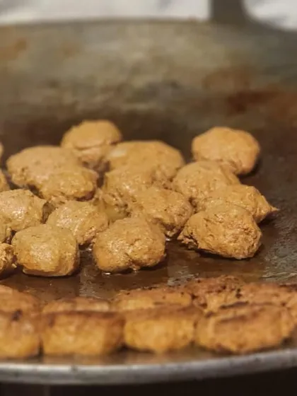 Freshly prepared Galouti kebabs sizzling on a traditional tawa. This close-up shot highlights the texture and preparation of one of our most requested Mughlai appetizers, known for its melt-in-the-mouth quality.
