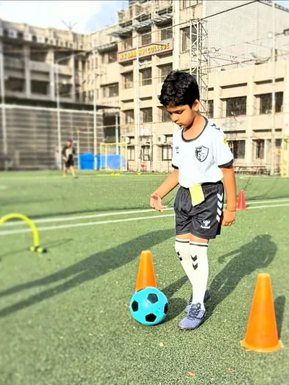 A young player pauses to assess his path through a cone and hurdle drill, learning to think strategically while maintaining ball control.
