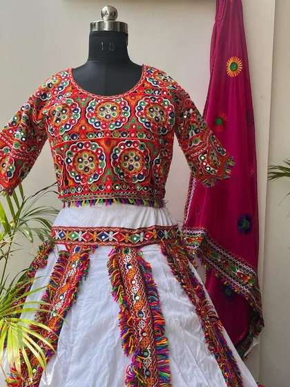 A classic white chaniya choli with colorful embroidery and a bright pink dupatta. This is a timeless and elegant choice for Navratri.