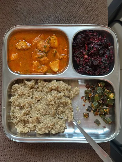 A plate with quinoa, chicken curry, and sautéed vegetables. This is a high-protein, gluten-free meal that is both satisfying and healthy.