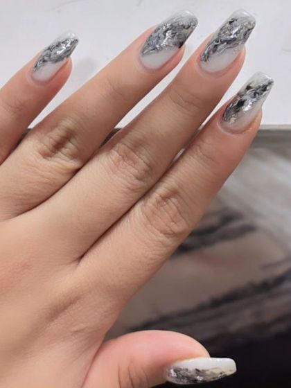 Another view of the shattered silver foil nails, showing the dynamic and reflective texture on long, square-shaped extensions.