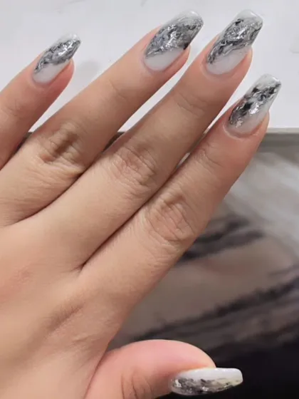 Another view of the shattered silver foil nails, showing the dynamic and reflective texture on long, square-shaped extensions.