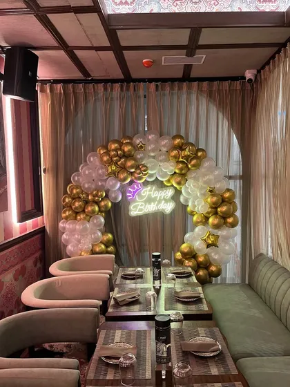 An elegant birthday setup in a private dining area of a restaurant. The gold and white balloon arch adds a touch of class to the celebration.