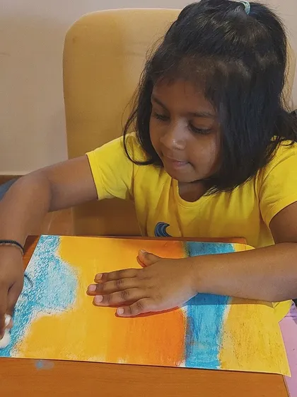 Another angle of our oil pastel seascape class, showing a student's concentration as she blends the colors of the sky and sea.
