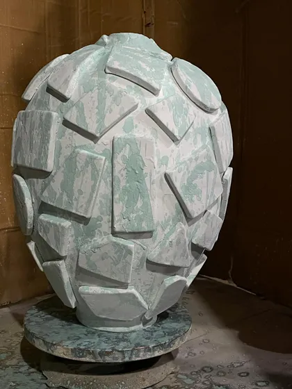 A large, sculptural piece before its final firing. The geometric shapes and pale green slip will be completely transformed by the heat of the kiln.