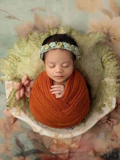 The full view of the artistic setup, showing the baby as the centerpiece against a stunning, soft focus floral background.
