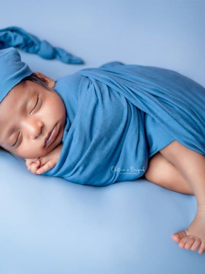 A sweet, side-lying pose of a newborn wrapped in a soft blue swaddle with a matching sleepy cap. This pose is perfect for capturing the peaceful, curled-up nature of a new baby.