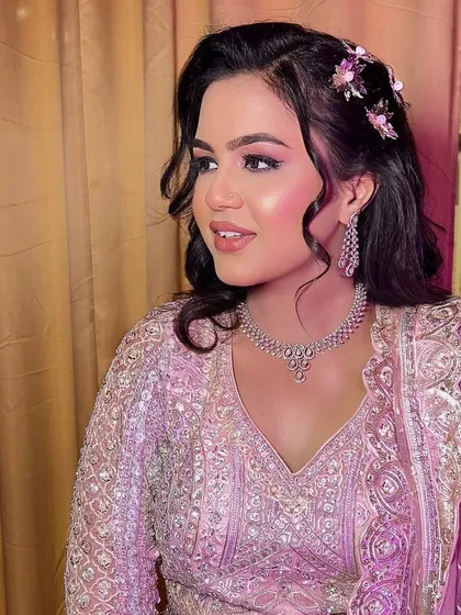 A side profile of the bride, highlighting her soft curls and the delicate diamond jewelry. The makeup is kept fresh and youthful, with a pop of pink on the cheeks and lips.