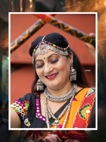 A close-up portrait of a woman ready for Garba. The focus is on her traditional silver jewelry and joyful expression, with dandiya sticks creating a nice frame, capturing the essence of Navratri celebrations.