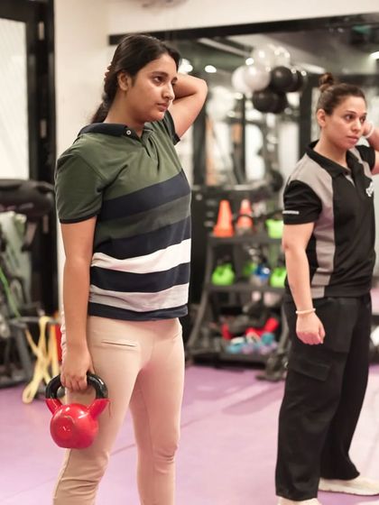 A female trainer works with a client on kettlebell exercises, showcasing the supportive and expert guidance we offer to all our members.