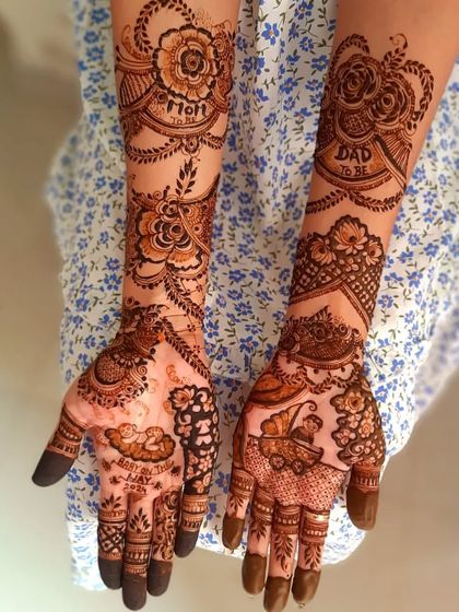 A full-arm baby shower design with 'Mom to be' and 'Dad to be' written on the forearms. The palms have drawings of a baby sleeping and a baby in a stroller.