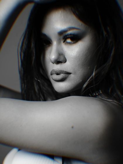 An intense and captivating close-up portrait. The selective focus and grainy texture of this black and white shot add a raw, cinematic quality, drawing all attention to the model's powerful gaze.