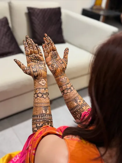 A happy bride showing off the back of her hands. The design is a beautiful mix of traditional patterns that complement her bridal look perfectly.