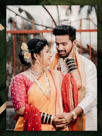 A candid moment of love and laughter. The bride looks lovingly at her groom, her smile radiant in her traditional orange and red Nauwari saree.