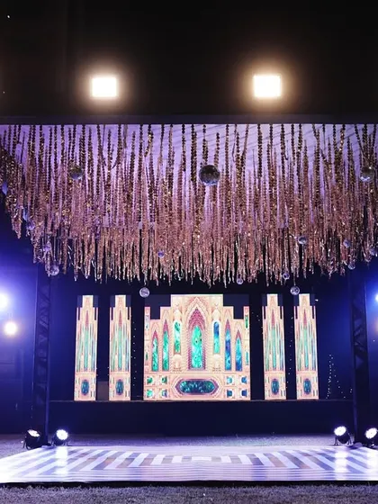 A high-tech Sangeet stage with a large LED screen backdrop and a shimmering tassel ceiling, perfect for showcasing videos and performances.