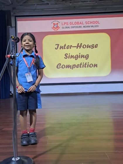 A young girl confidently sings for her house during the competition, showcasing the talent present in our junior classes.