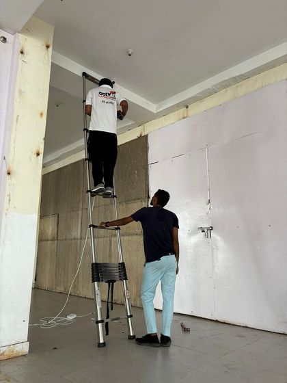 Safety is key during any installation. Here, one team member secures the ladder while the other works on the ceiling, ensuring a safe and efficient process.