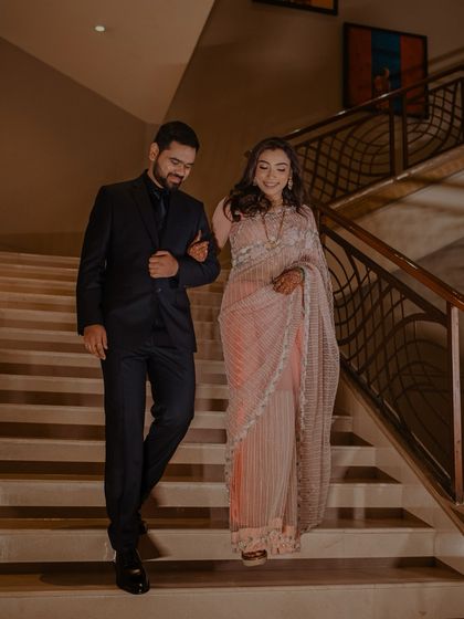 A candid shot of the couple descending a staircase, arm in arm. Their shared smile and easy elegance make this a beautiful, natural portrait.