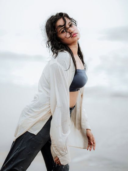 This image captures a strong, confident pose against a cloudy sky. The wet hair and casual styling give it a raw and authentic feel.