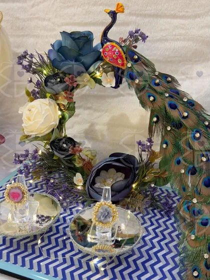 For your engagement, the ring platter should be as unique as your love story. This peacock-themed ring platter, adorned with rich blue and white florals and twinkling lights, creates a magical moment for the ring exchange ceremony.