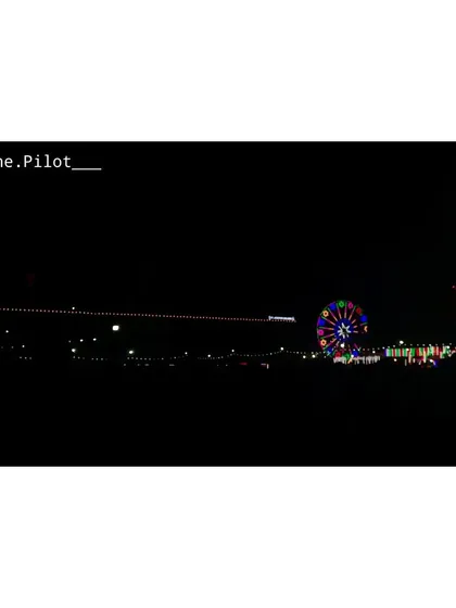 A distant shot of a Christmas Mela in Prayagraj. The colorful Ferris wheel stands out against the night, capturing the fun and festive spirit of the fair.