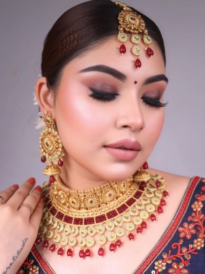 Bridal elegance unveiled. This look features a classic bridal smokey eye with a touch of gold, paired with a traditional red and gold jewelry set.