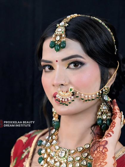 A classic bridal look featuring a beautiful matha patti and nath. The makeup is kept elegant with a focus on defined eyes and glowing skin to complement the heavy jewelry.