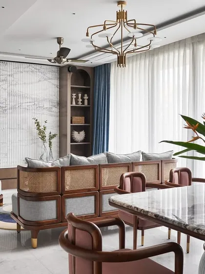 A view of the living room highlighting the custom-designed sofa and lounge chairs, which blend wood and cane for a rustic, Zen-like feel. The fluted Satvario marble TV unit wall adds a touch of opulence and visual height.