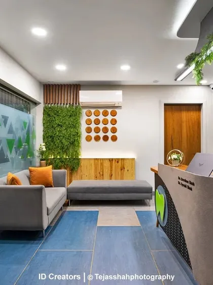 The 'Smile Dente' dental clinic in Vadodara features a welcoming reception and waiting area with a playful blue floor, comfortable seating, and biophilic elements.