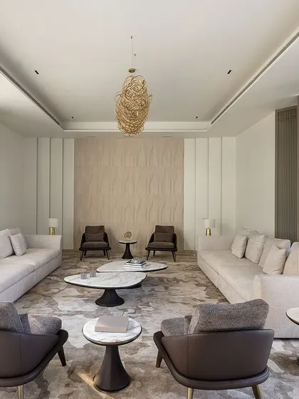 This living area is designed for comfortable and stylish gatherings. The symmetrical arrangement of sofas, complemented by modern armchairs and side tables with gold accents, creates a balanced and aesthetically pleasing composition.