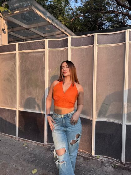 An orange halter top paired with ripped, wide-leg jeans for a sunny day out.