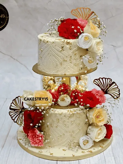 A radiant two-tier engagement cake with an illuminated spacer. This 3kg chocolate cake features a self-engraved pattern, gold leaf, and is decorated with red and white fresh flowers.