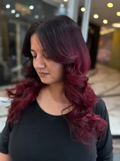 A side profile of this red-violet look, styled with soft, glamorous curls.
