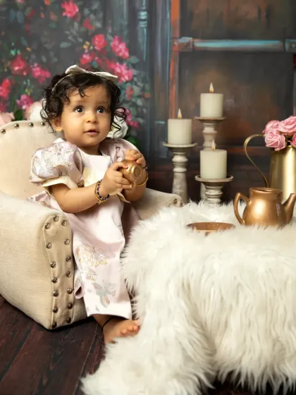 A curious moment, reaching for a tiny golden teacup. These themed sessions are wonderful for capturing your baby's imagination.