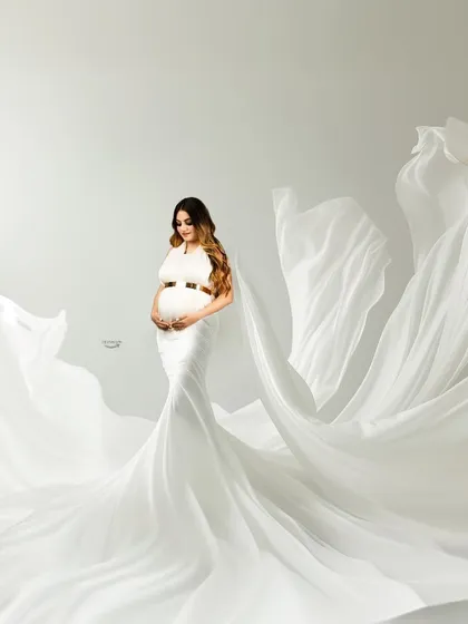 A breathtaking shot featuring a white gown with fabric tossed to look like angel wings. The clean, high-key background gives this portrait an ethereal and heavenly quality.