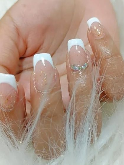 A close-up of the rhinestone accent on the ring finger of this sparkling French manicure set.