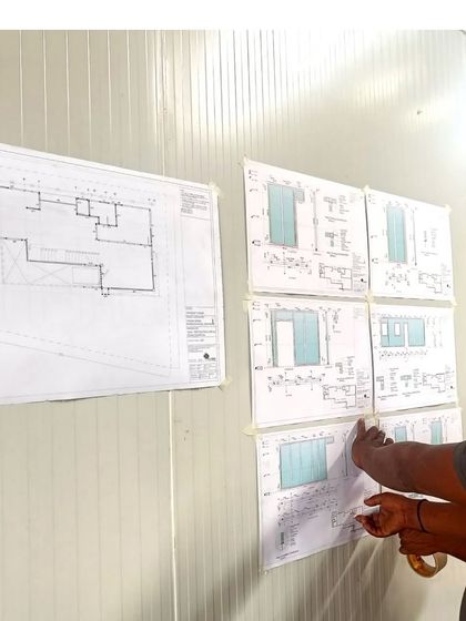 An architect reviewing the detailed drawings on-site against the installed panels. Precision is key when working with prefabricated systems, and we ensure every component fits perfectly as planned.