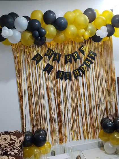 A shimmer curtain is a great way to create a simple photo backdrop. For this setup, I used a gold curtain with a "Happy Birthday" banner and a black, gold, and white balloon garland at the top.