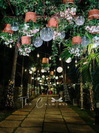 An enchanting entranceway for a reception, with a canopy of hanging baskets, disco balls, and warm lights creating a magical, immersive experience.