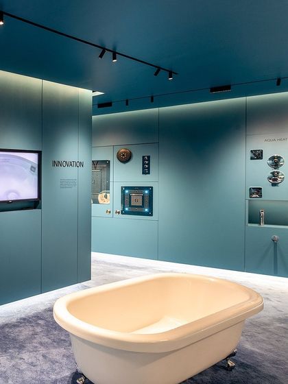 Another angle of the showroom, highlighting the contrast between the classic form of the bathtub and the modern, technical display of shower components on the wall.
