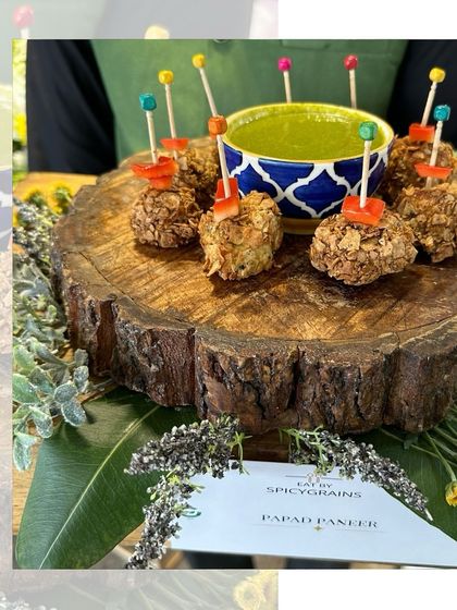 Crispy Papad Paneer bites served with a vibrant green chutney on a rustic wooden log platter. A perfect fusion appetizer.