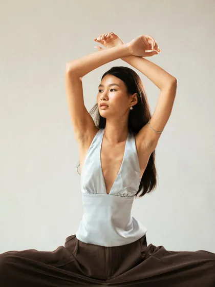 A powerful and symmetrical pose that showcases the V-neck design of the top. The lighting sculpts the model's form, creating a strong, high-fashion image.