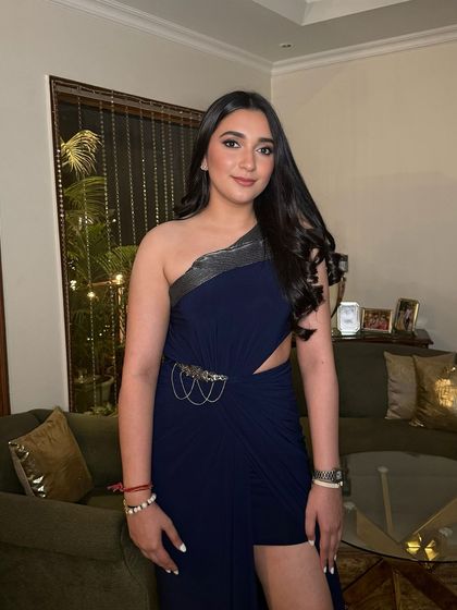 A full-length view of this gorgeous bronzed glam. The makeup enhances her features beautifully, pairing perfectly with her chic navy blue dress for a sophisticated evening look.