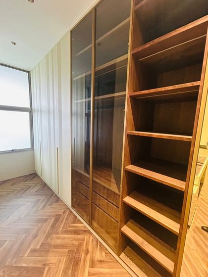 A combination of open shelving, drawers, and closed cabinets with glass doors provides a variety of storage options in this custom walk-in closet. The natural wood finish adds warmth to the space.