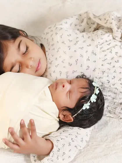 The peaceful bond between sisters. This newborn photo captures a quiet moment with an older sister sleeping soundly next to her new baby sibling.
