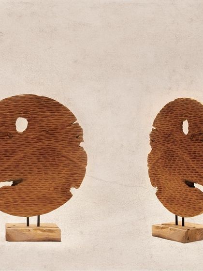 These two disc-shaped artifacts are carved with a ribbed texture and feature natural imperfections. They have an almost mask-like quality, adding a touch of mystery and character.