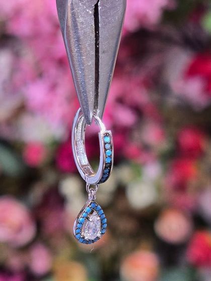 A stunning teardrop-shaped hanging with turquoise and diamond-like stones, perfect for adding a pop of color to your look.