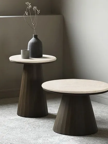 A pair of round side tables with a modern, minimalist design. The tops are made of light-colored marble, creating a luxurious look, while the conical, faceted bases are finished in a warm wood veneer.