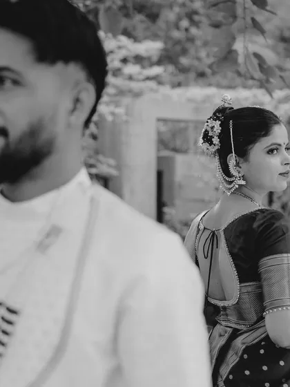 An artistic shot in black and white, focusing on the bride's traditional hairstyle and jewelry. The groom is blurred in the foreground, creating a sense of depth and narrative.
